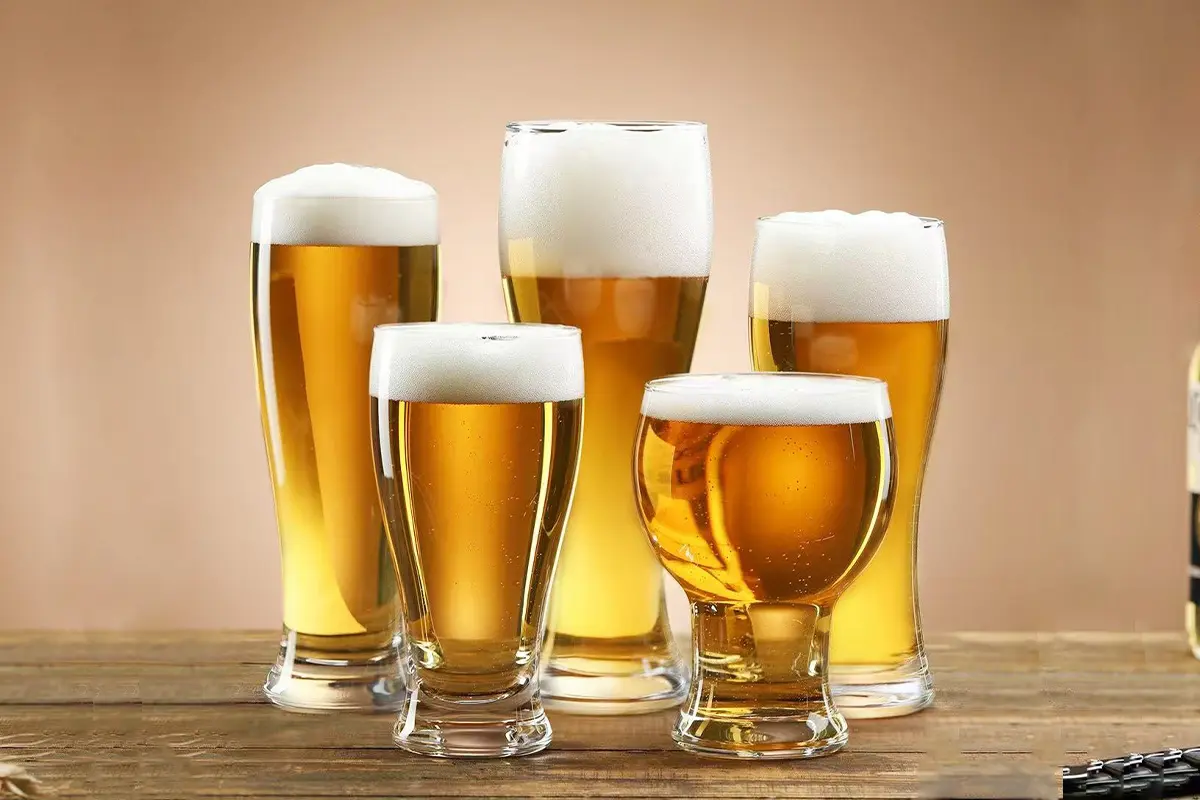 Collection of beer glasses by style filled with golden beer on a wooden table
