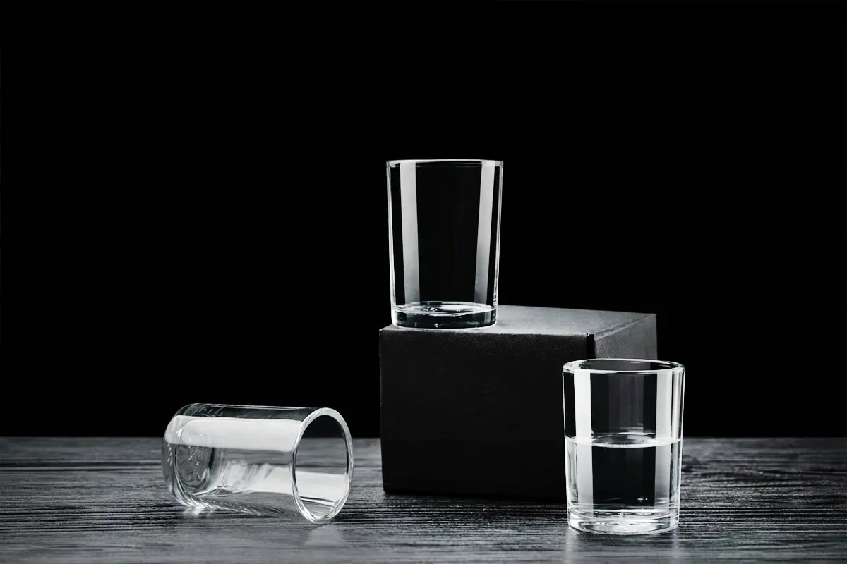 Clear shot glasses for spirits displayed on a black background