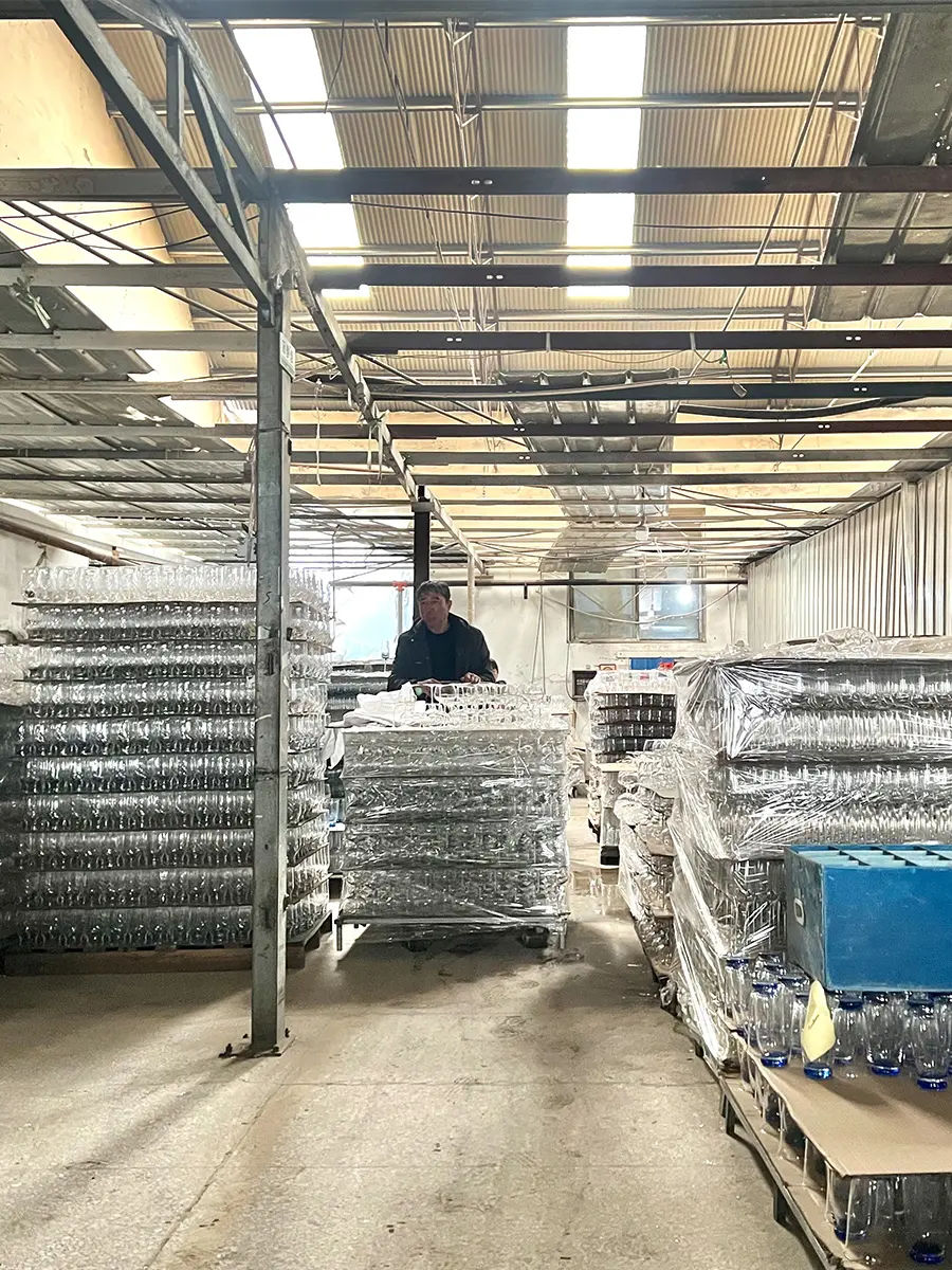 Factory worker handling trays of glassware during daily production operations